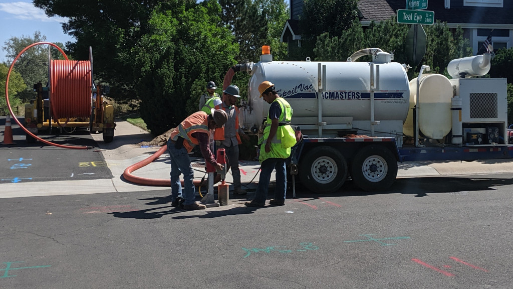 construction workers using a core drill to bore through asphalt road surface